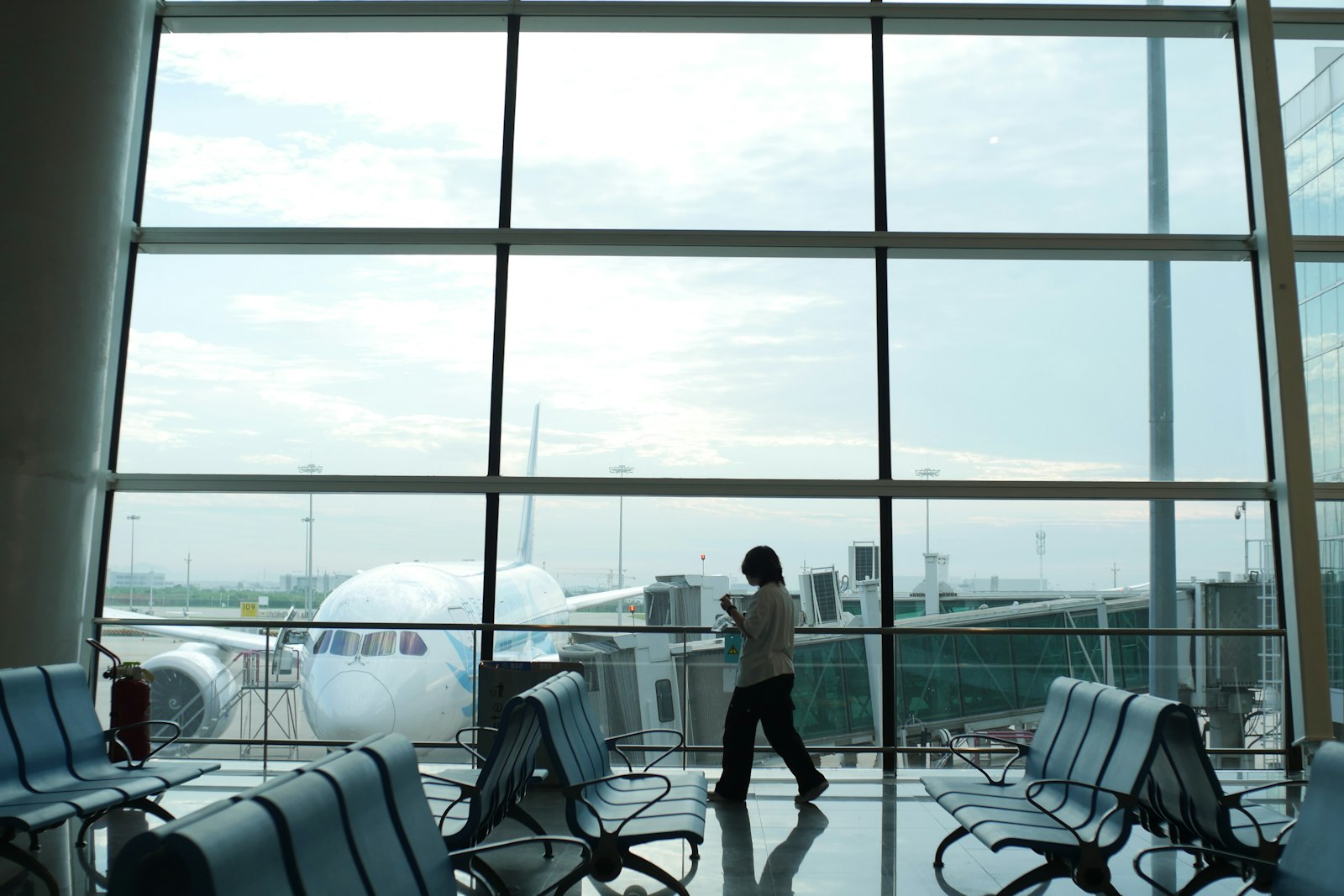 A traveler at an airport window looking out at a plane