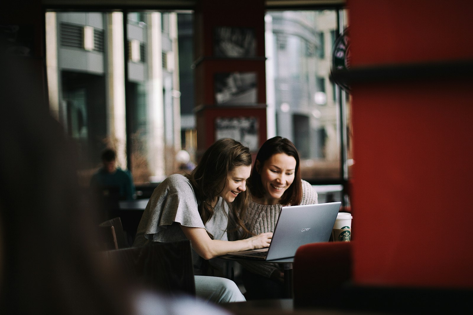 Two women looking at a laptop in a cafe